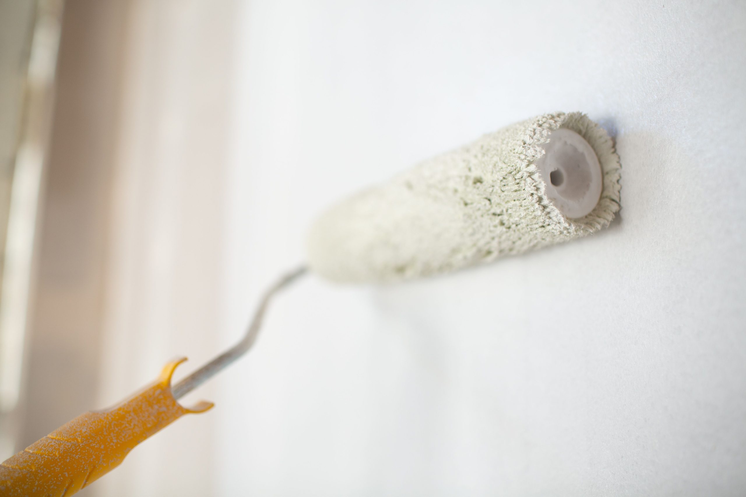 A Collingwood Painters paint roller applying white paint to a wall.