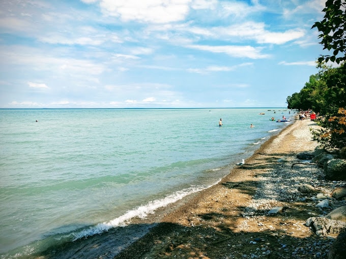 A sandy beach in Meaford with people swimming in the water.