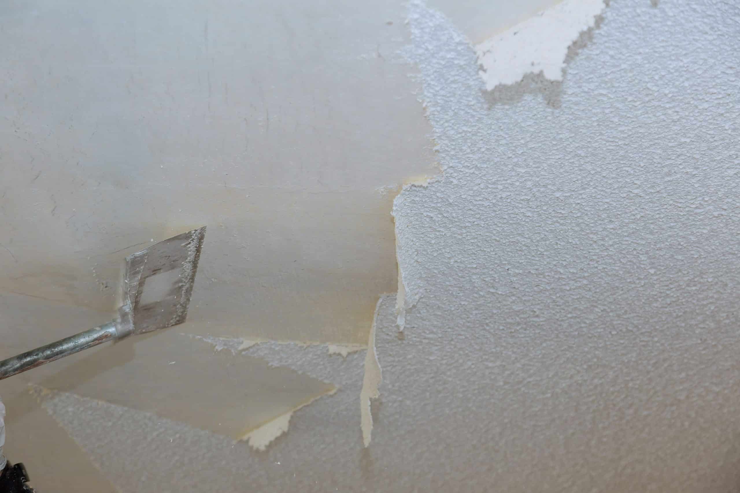 A man is removing plaster from a ceiling for removal services.