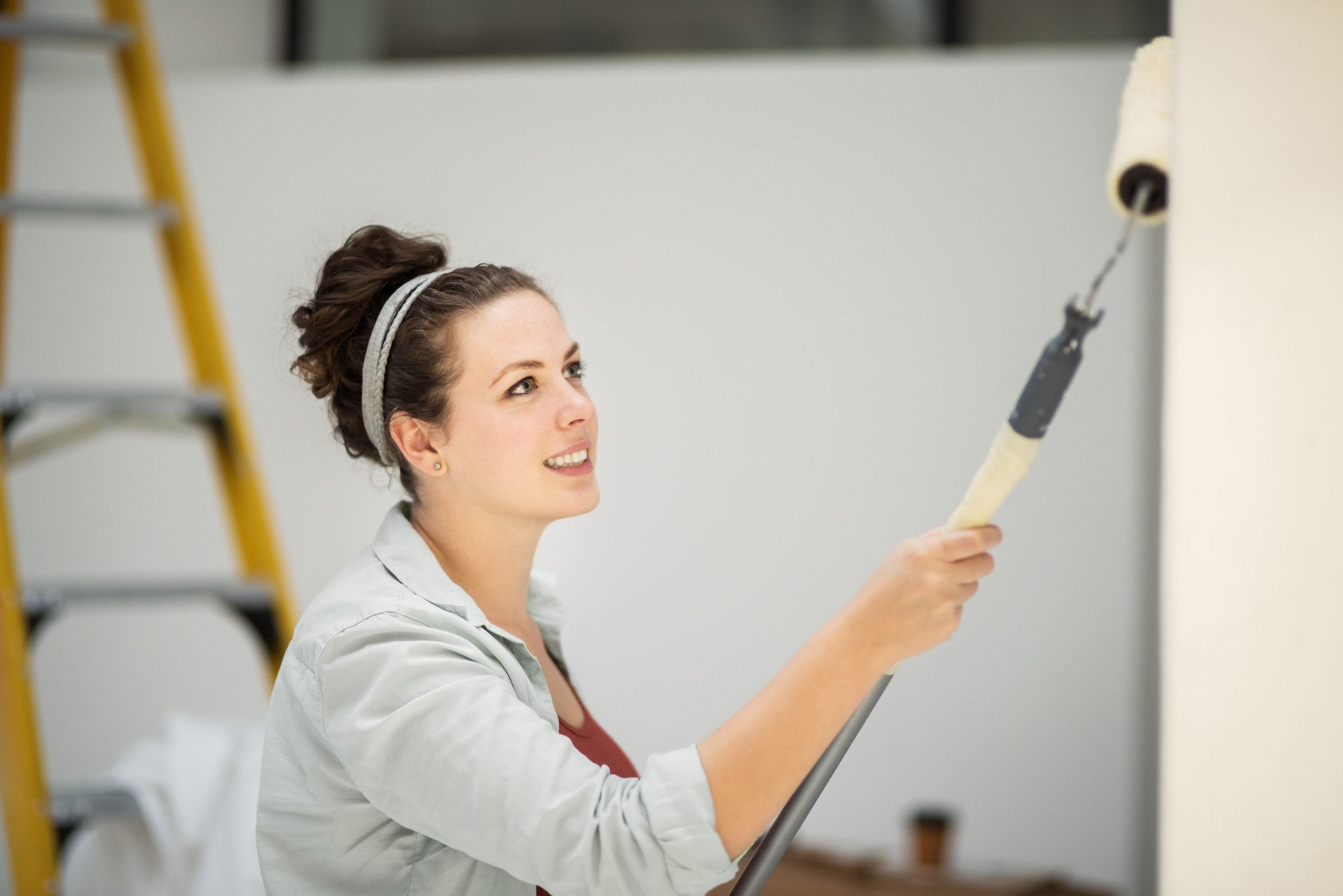 A woman from Collingwood painting a room with a paint roller.