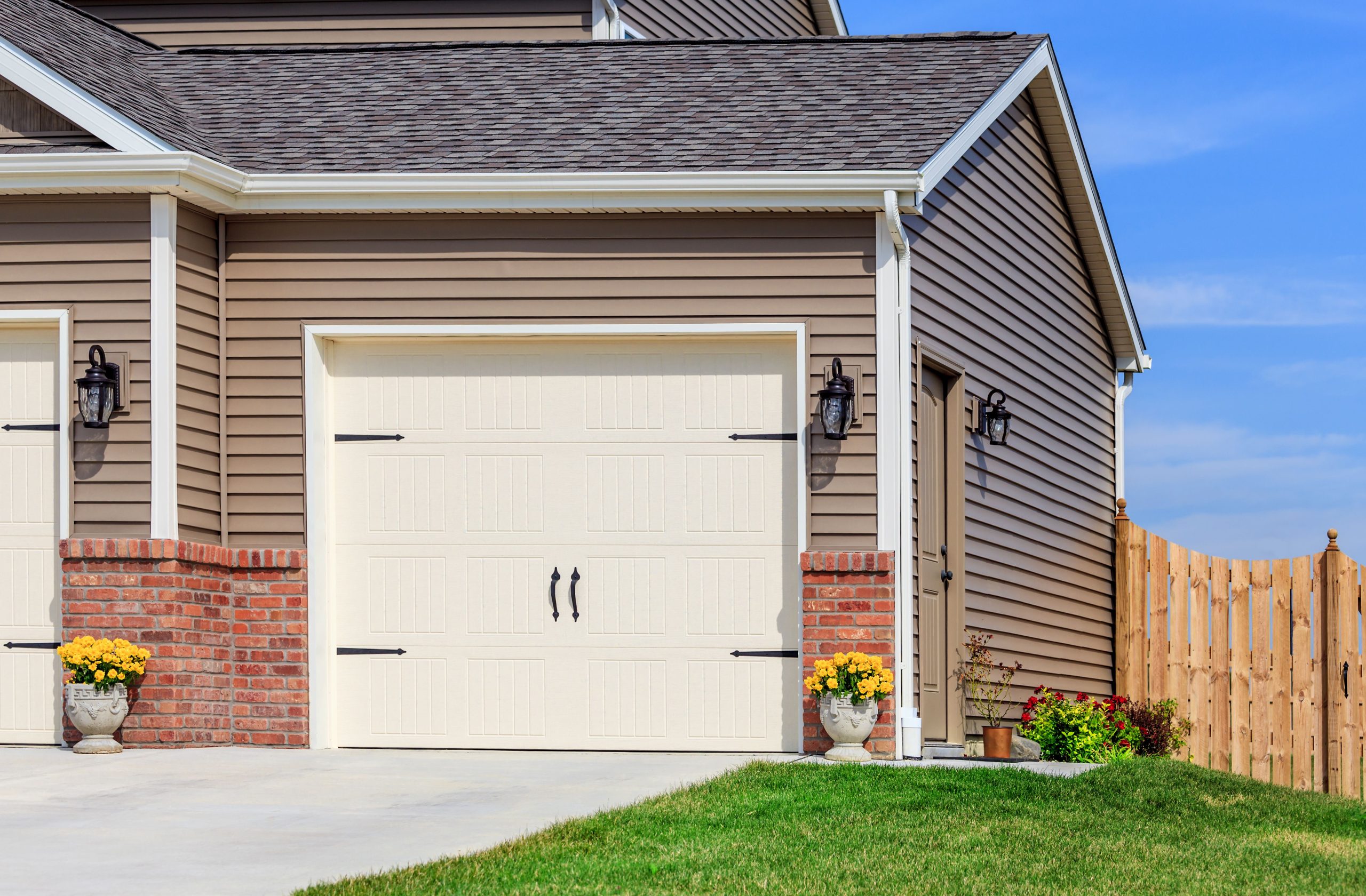 A house with two freshly painted garage doors in front of it.