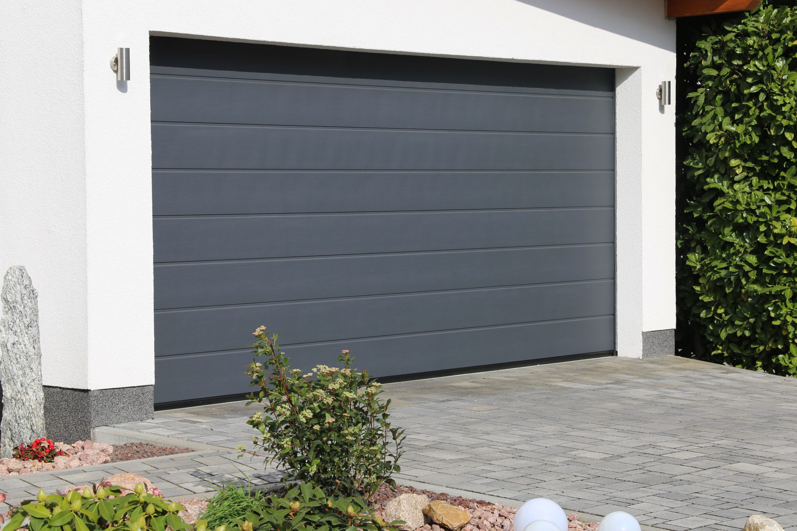 A garage door with plants in front of it.