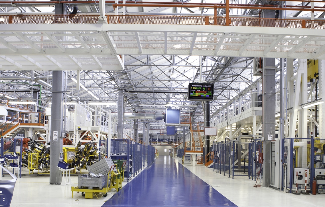 A spacious, modern manufacturing facility with machinery, a blue walkway, and a large digital clock display hanging from the ceiling offers top-tier commercial painting services in Collingwood.